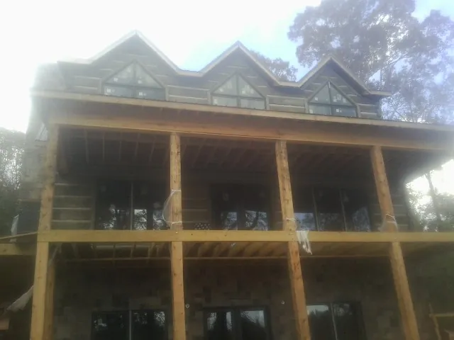 Dormers and porch framing on a large log home under construction — Roof Coating work by our crew in Jemison