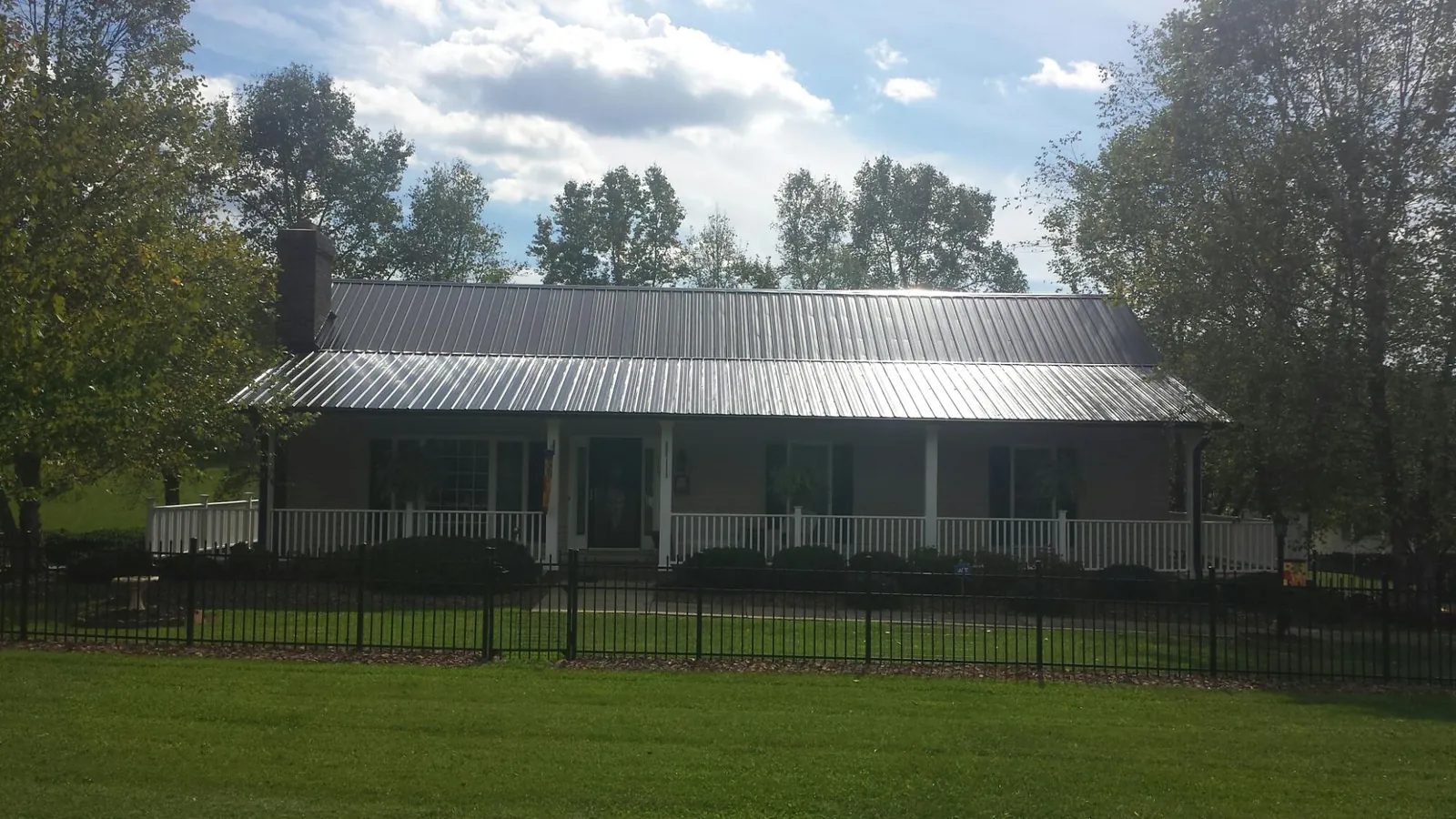 Gray metal roof on a brick ranch with a full width front porch — Gutter Guard Installation work by our crew in Jemison