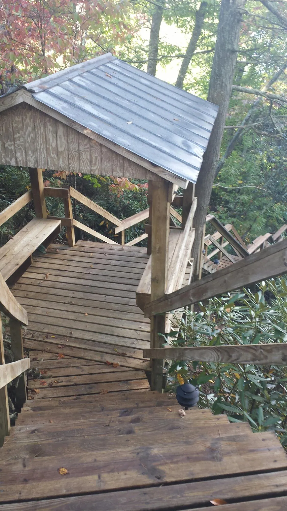 Metal roofed shelter over wooden steps on a wooded walkway — Skylight Repair & Installation work by our crew in Jemison