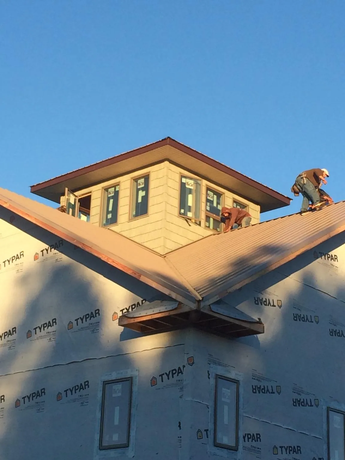 Roofers working around a rooftop cupola on a new metal roof at sunset — Roof Waterproofing in Jemison by Roofing Brothers